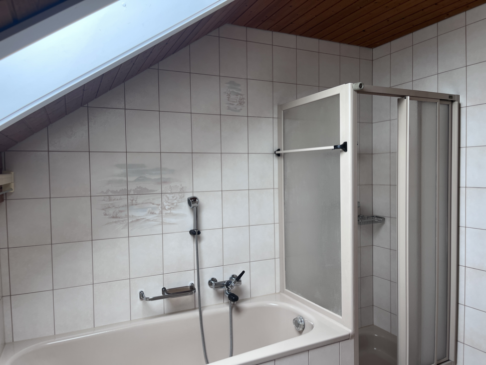 Badezimmer mit Badewanne und Dusche unter Schräge