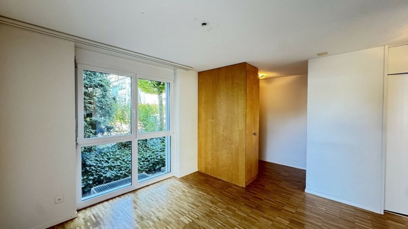 Heller Raum mit großem Fenster und Holzschrank