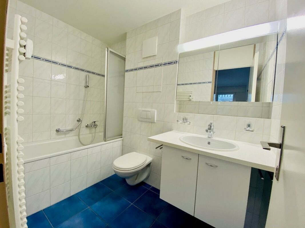 Badezimmer mit weißer Fliesenoptik und blauem Boden