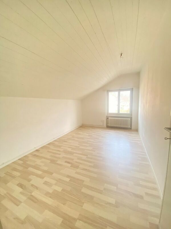 Ausgebautes Dachzimmer mit Fenster und Heizkörper