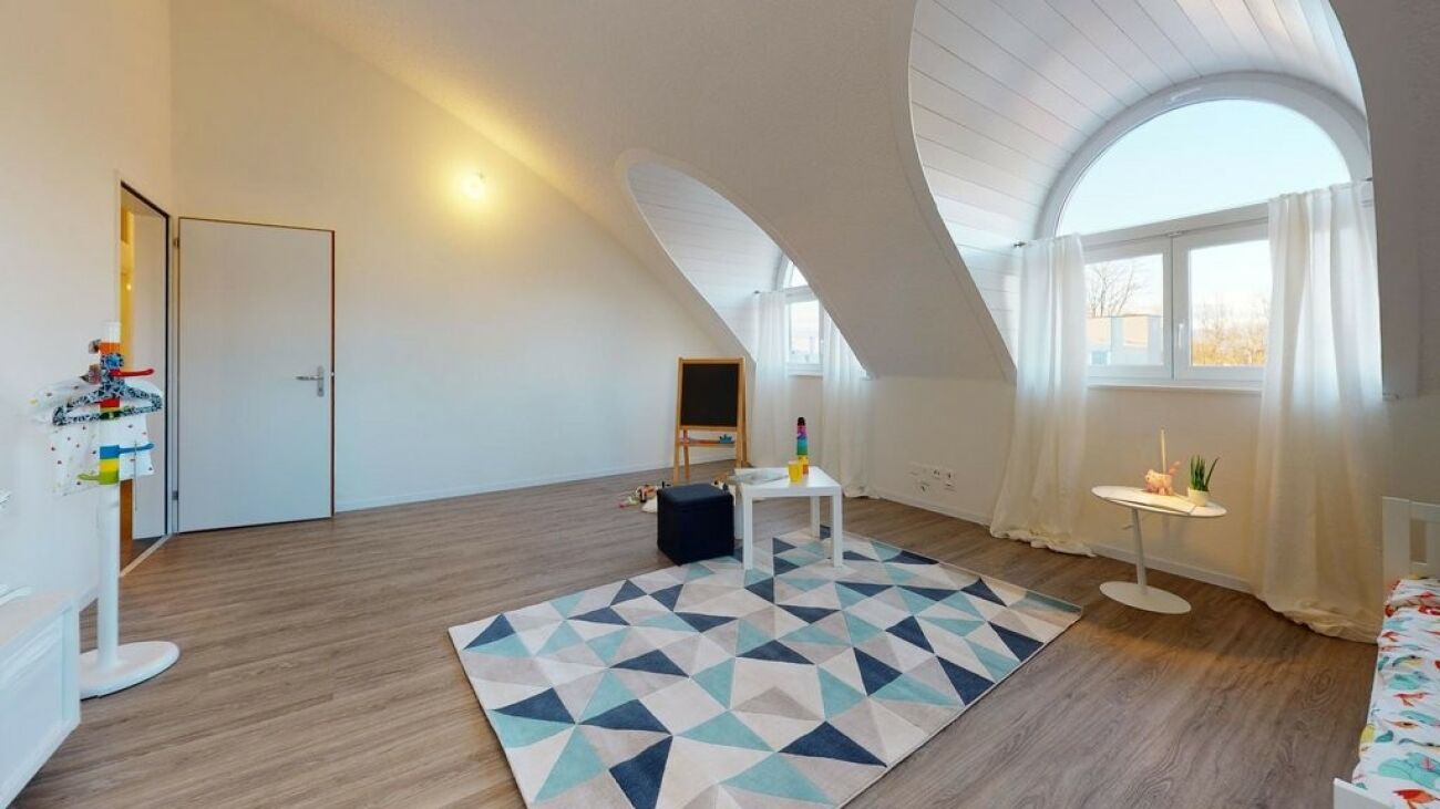 Dachgeschosszimmer mit großem Bogenfenster