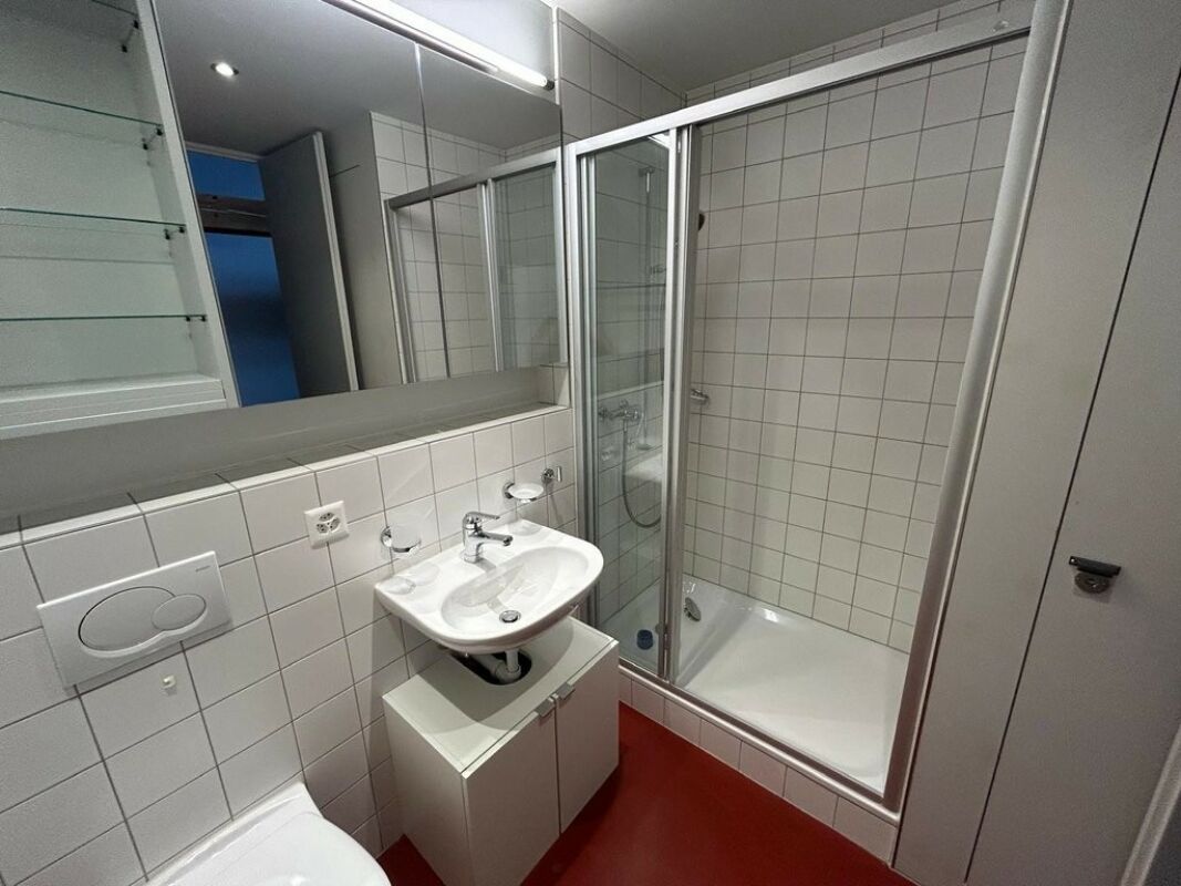 Kleines Badezimmer mit Duschkabine und rotem Boden