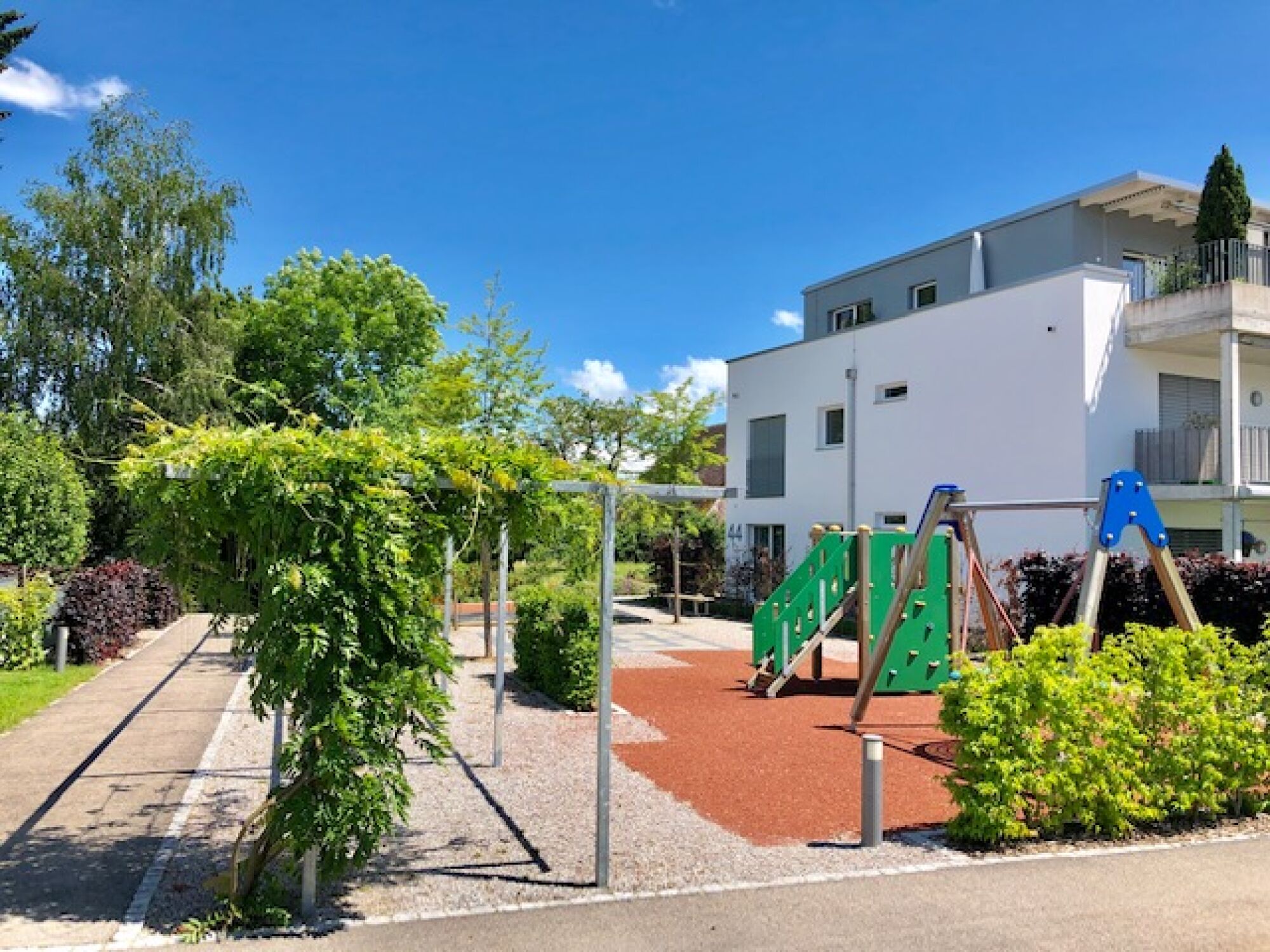 Außenbereich mit Spielplatz neben modernem Wohngebäude