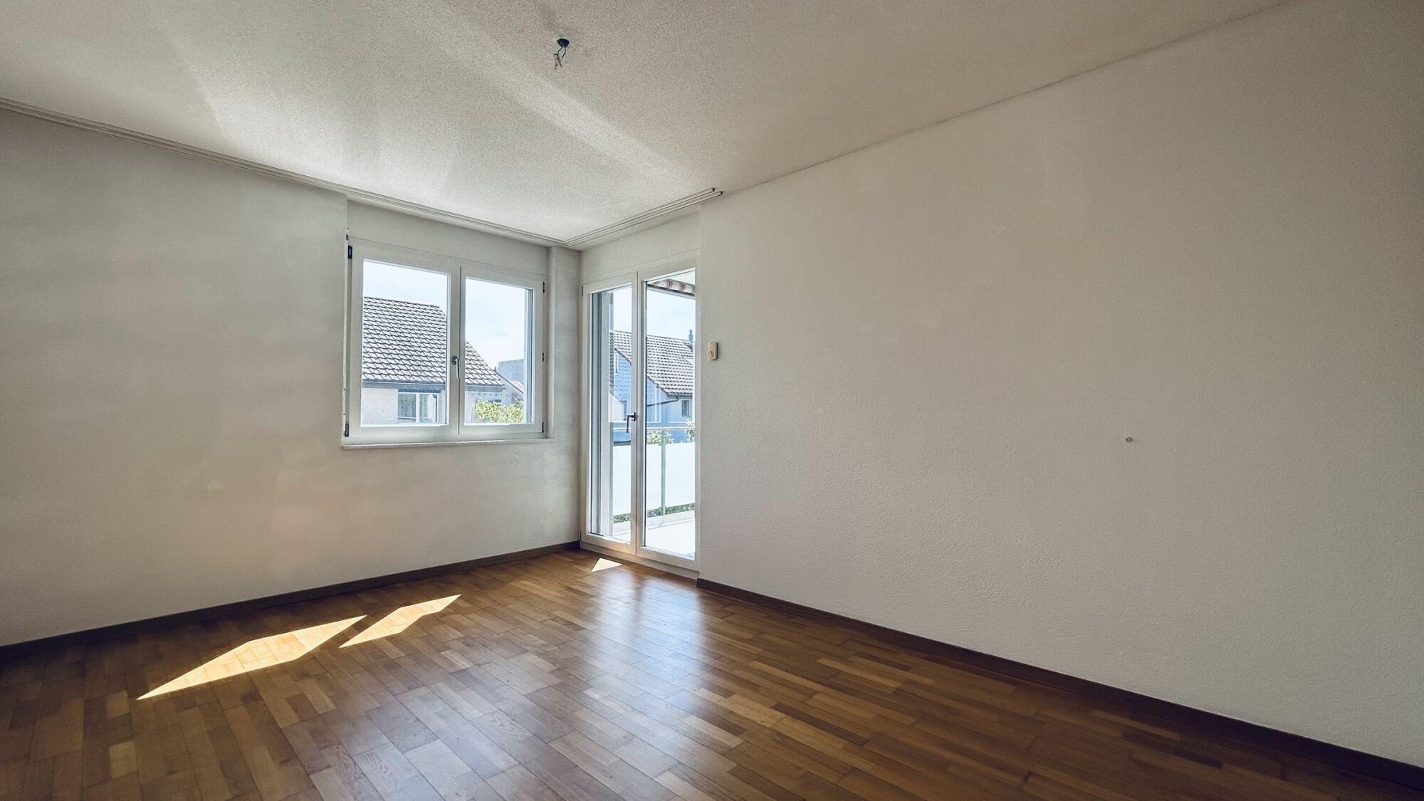 Heller leerer Wohnraum mit Balkon- und Fensterblick