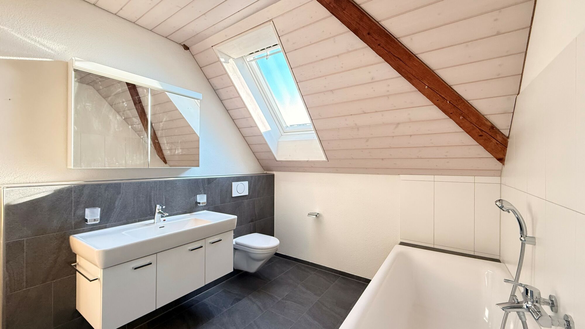 Modernes Dachgeschossbad mit Badewanne und Dachfenster