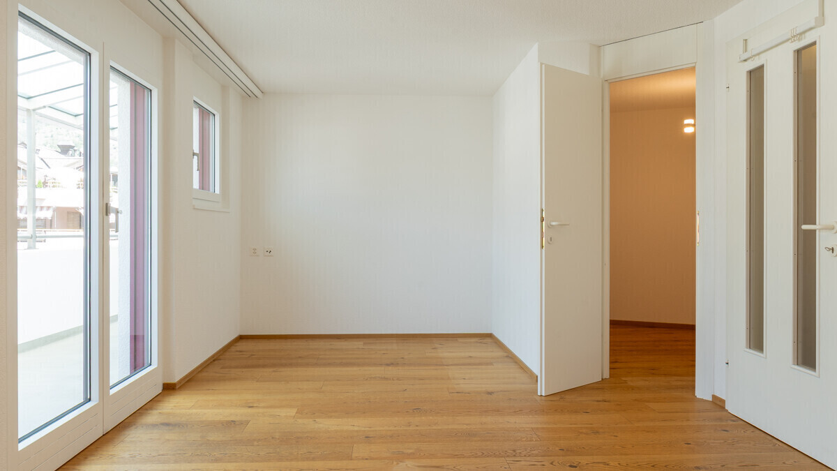 Heller leerer Raum mit Holzboden und mehreren Türen