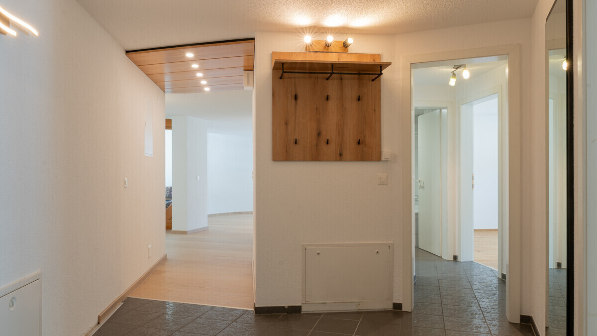 Heller Eingangsbereich mit Garderobenwand und Durchgang zu Wohnräumen