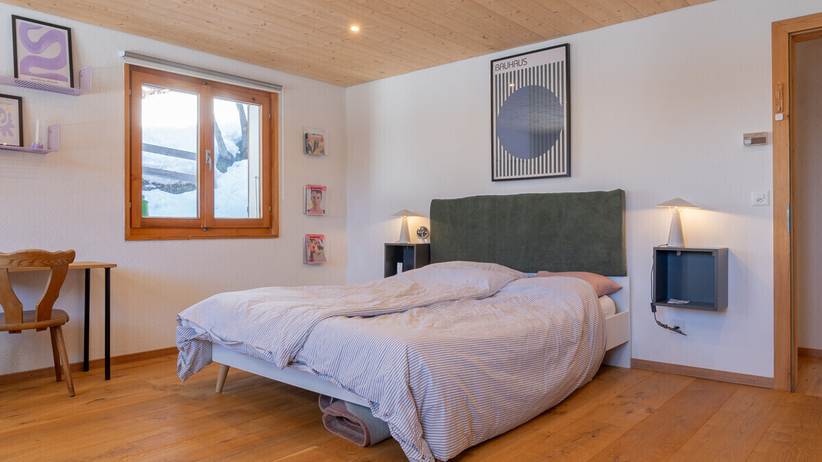 Helles Schlafzimmer mit Holzdecke und grünem Kopfteil