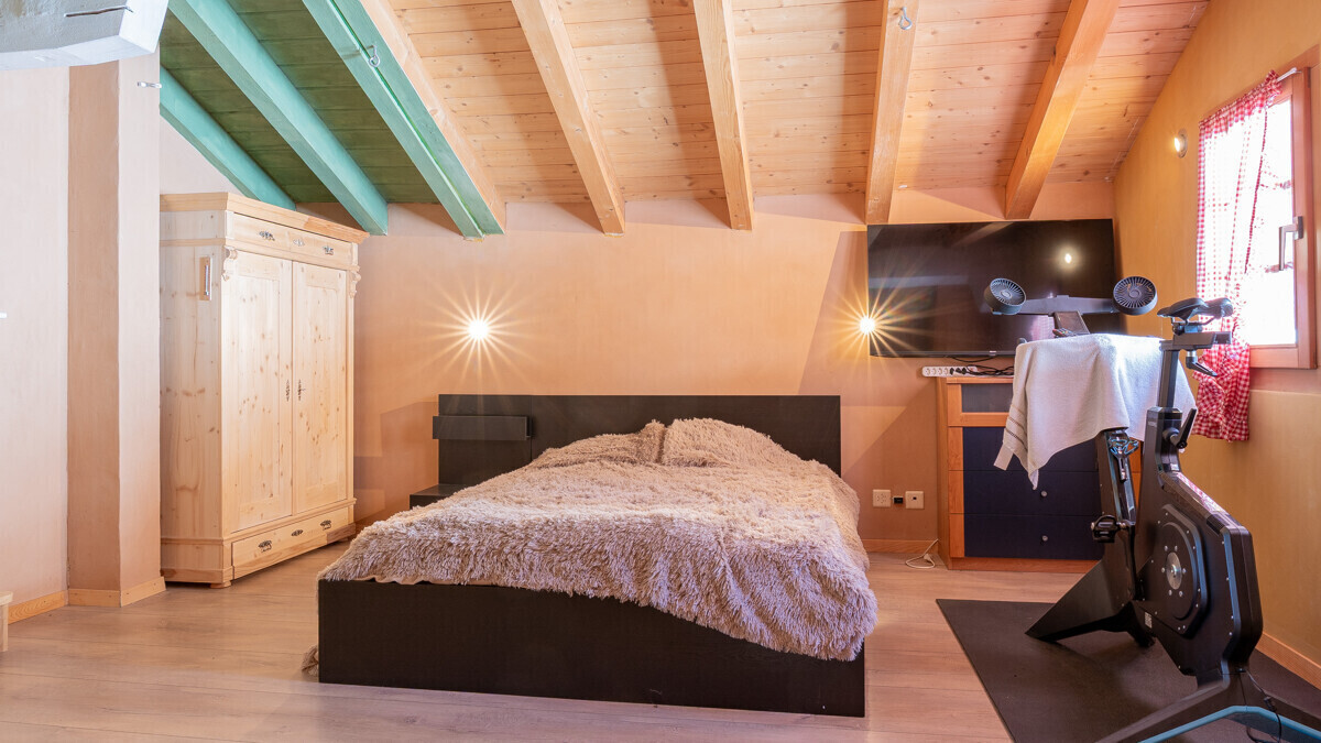 Gemütliches Schlafzimmer mit Holzdecke und Fitnessbereich