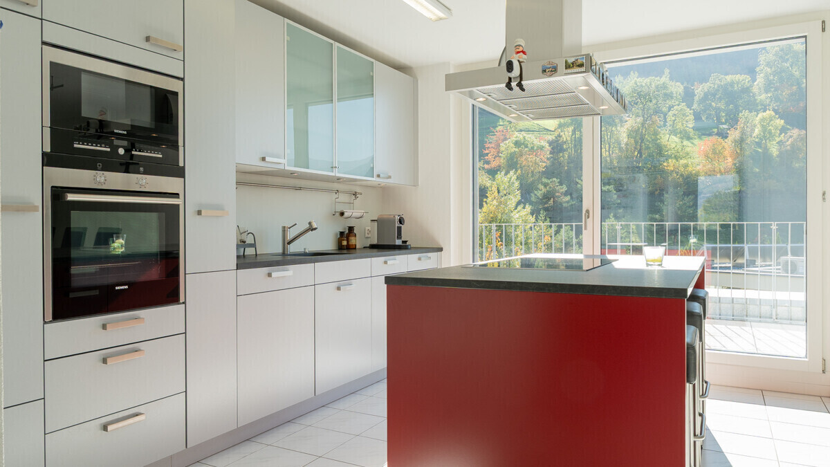 Moderne Küche mit roter Kochinsel und Gartenblick