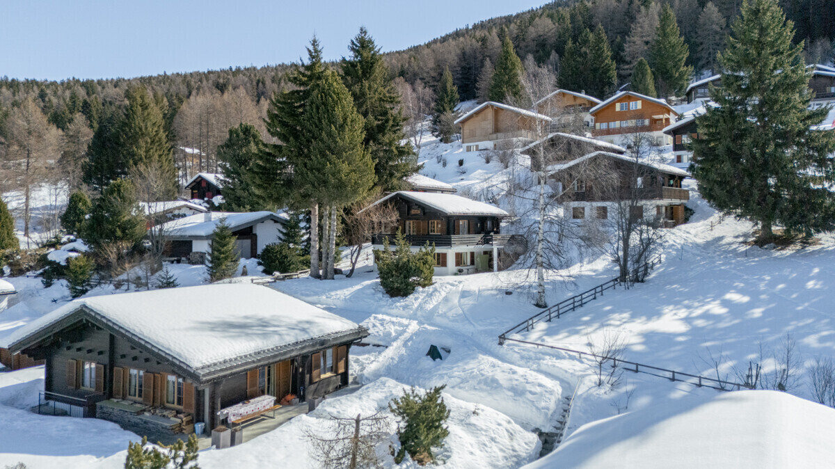 Verschneite Chalet-Häuser in alpiner Hanglage