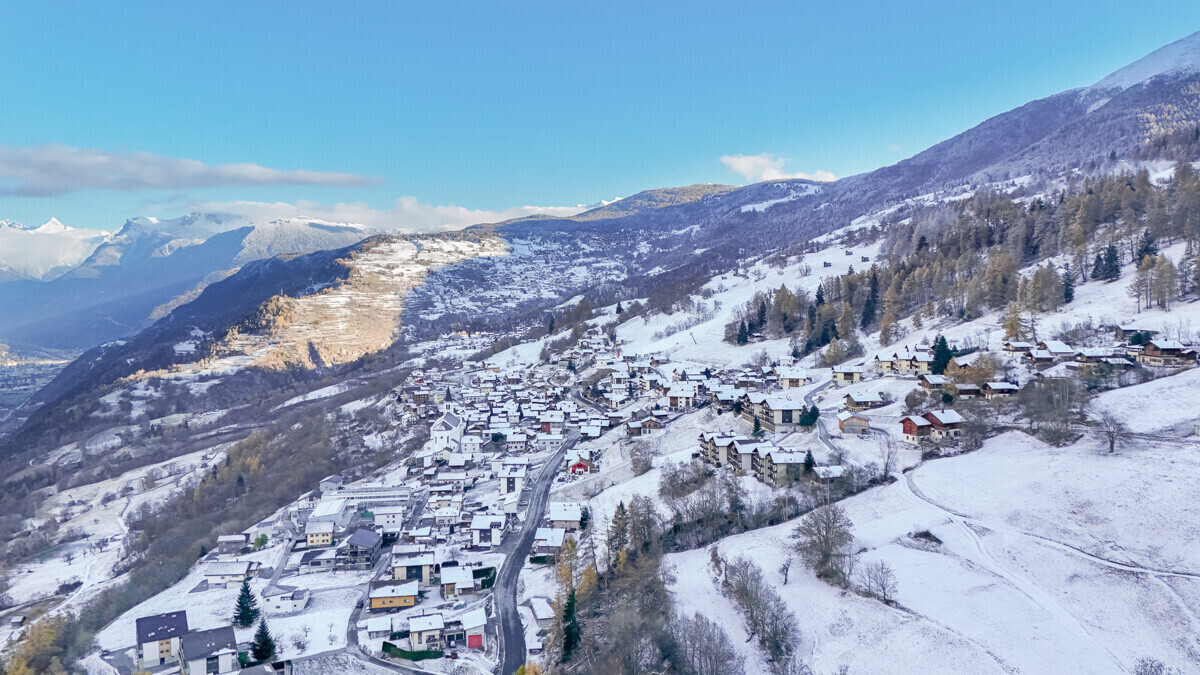Schneebedecktes Bergdorf in alpiner Tallandschaft