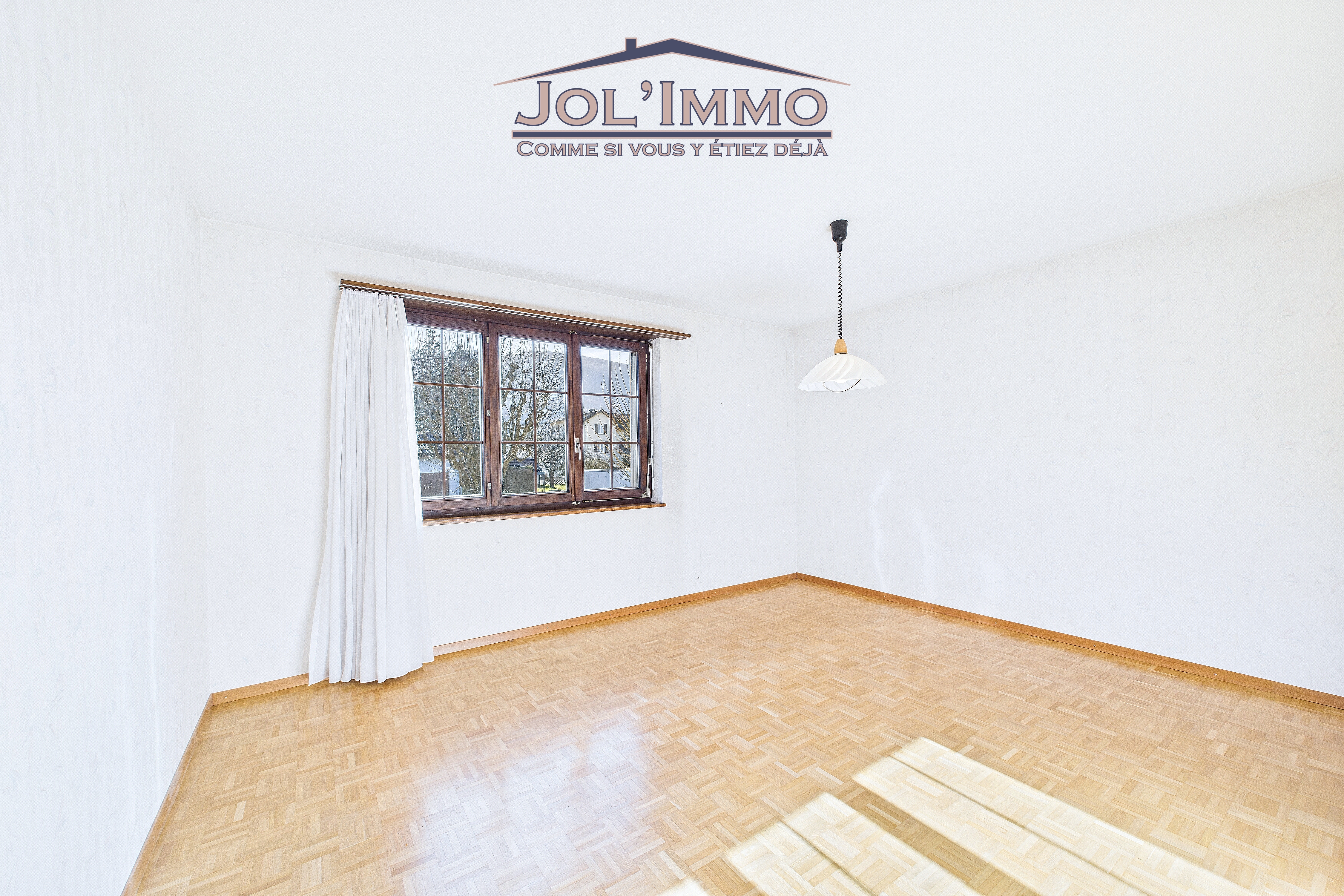 Leerer Wohnraum mit Parkettboden und Fenster