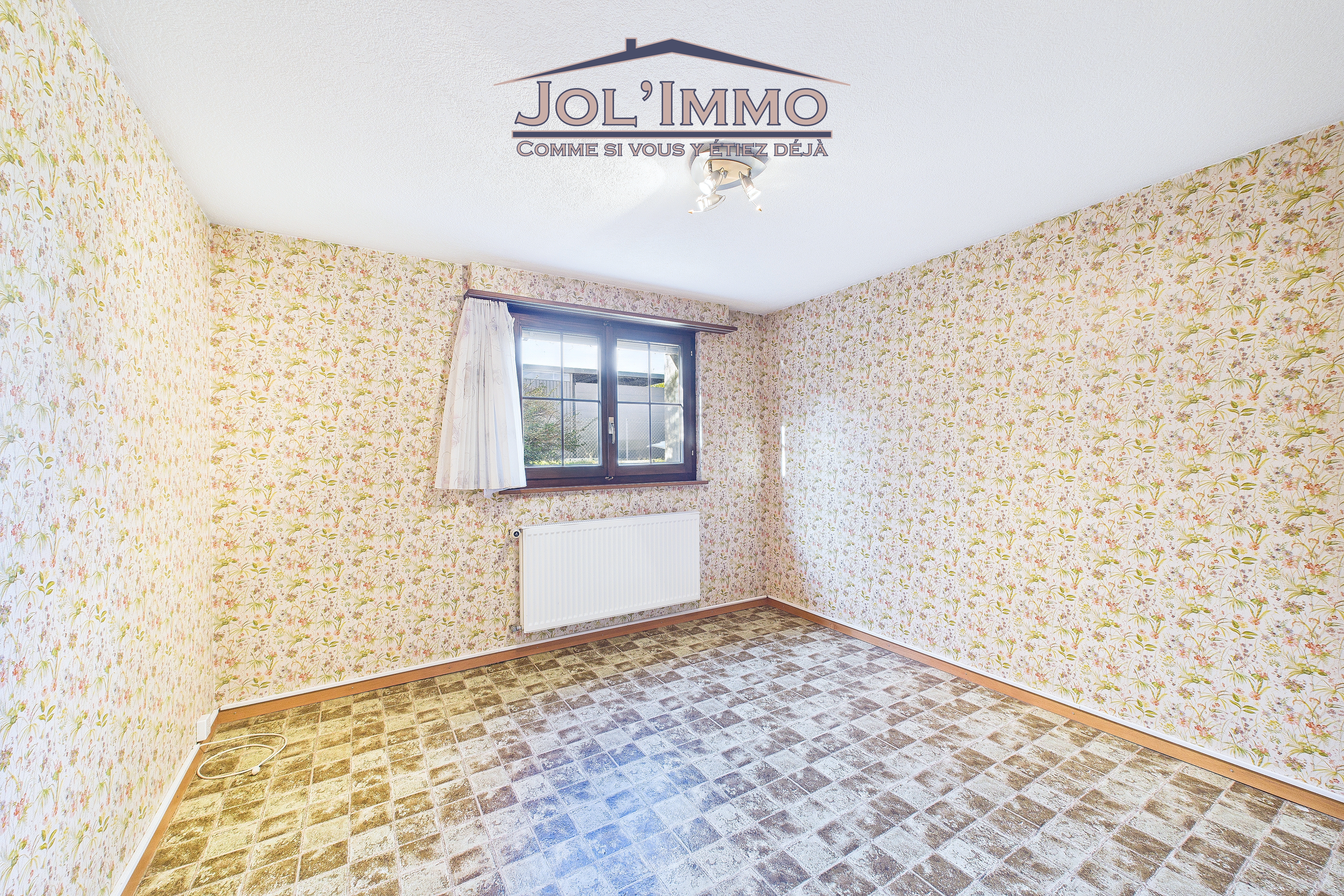 Schlafzimmer mit gemusterten Tapeten und Fenster