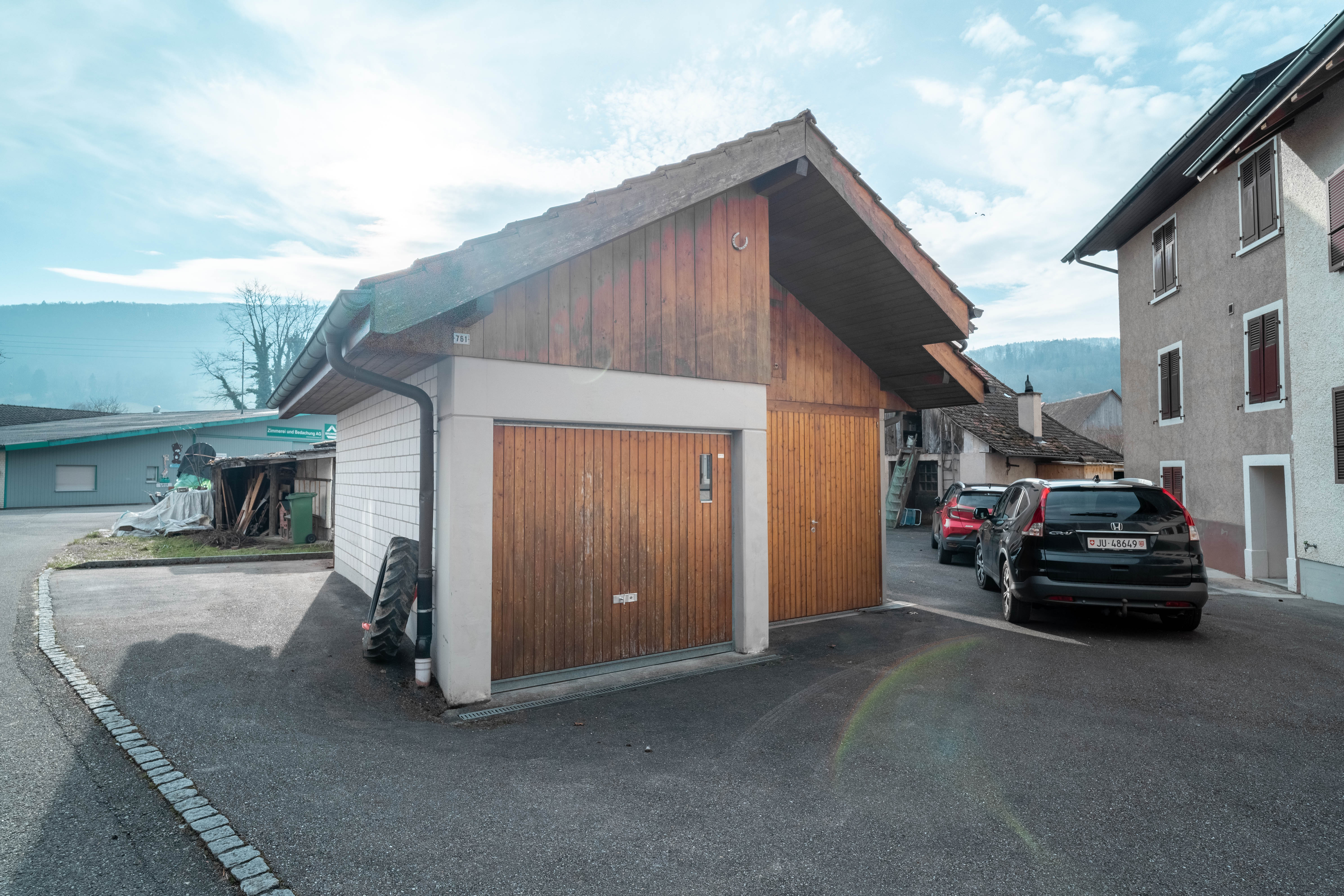 Außenansicht eines Nebengebäudes mit Holzfassade und Garagentor