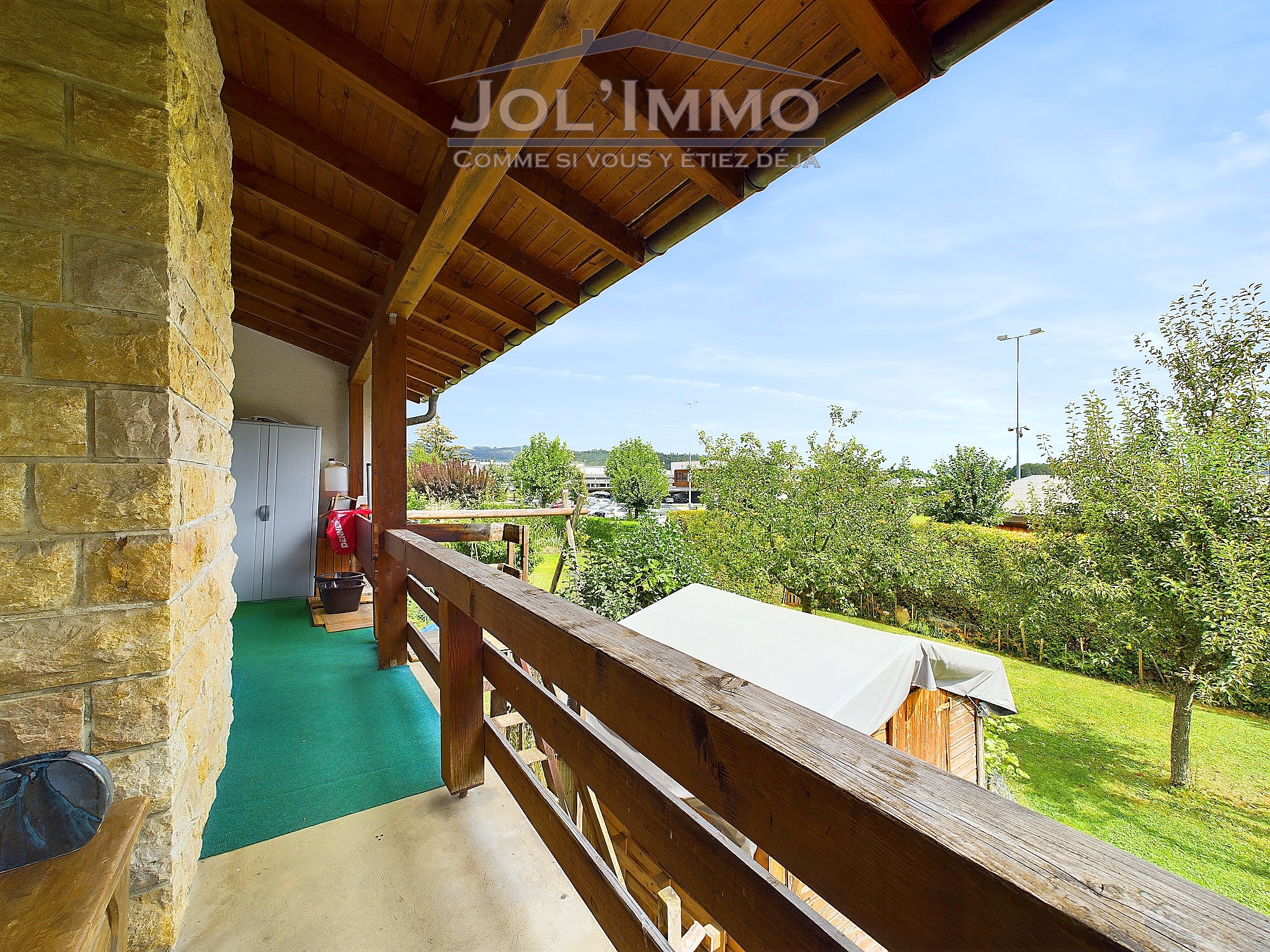 Überdachter Balkon mit Holzdetails und Gartenblick