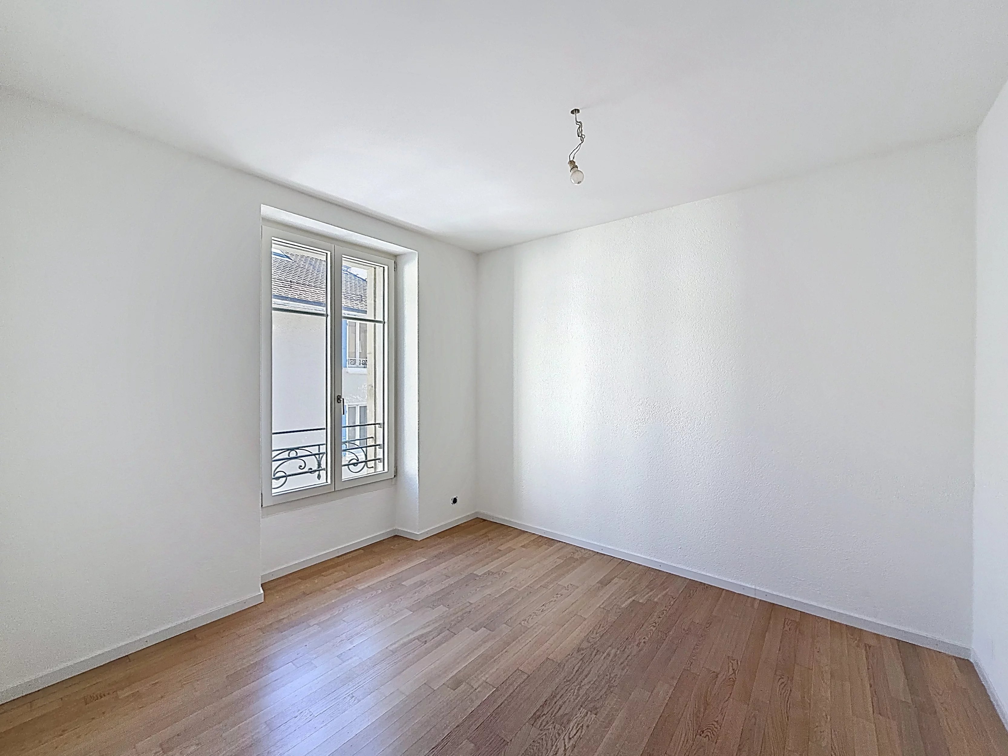 Leerer heller Raum mit Parkett und Fenster