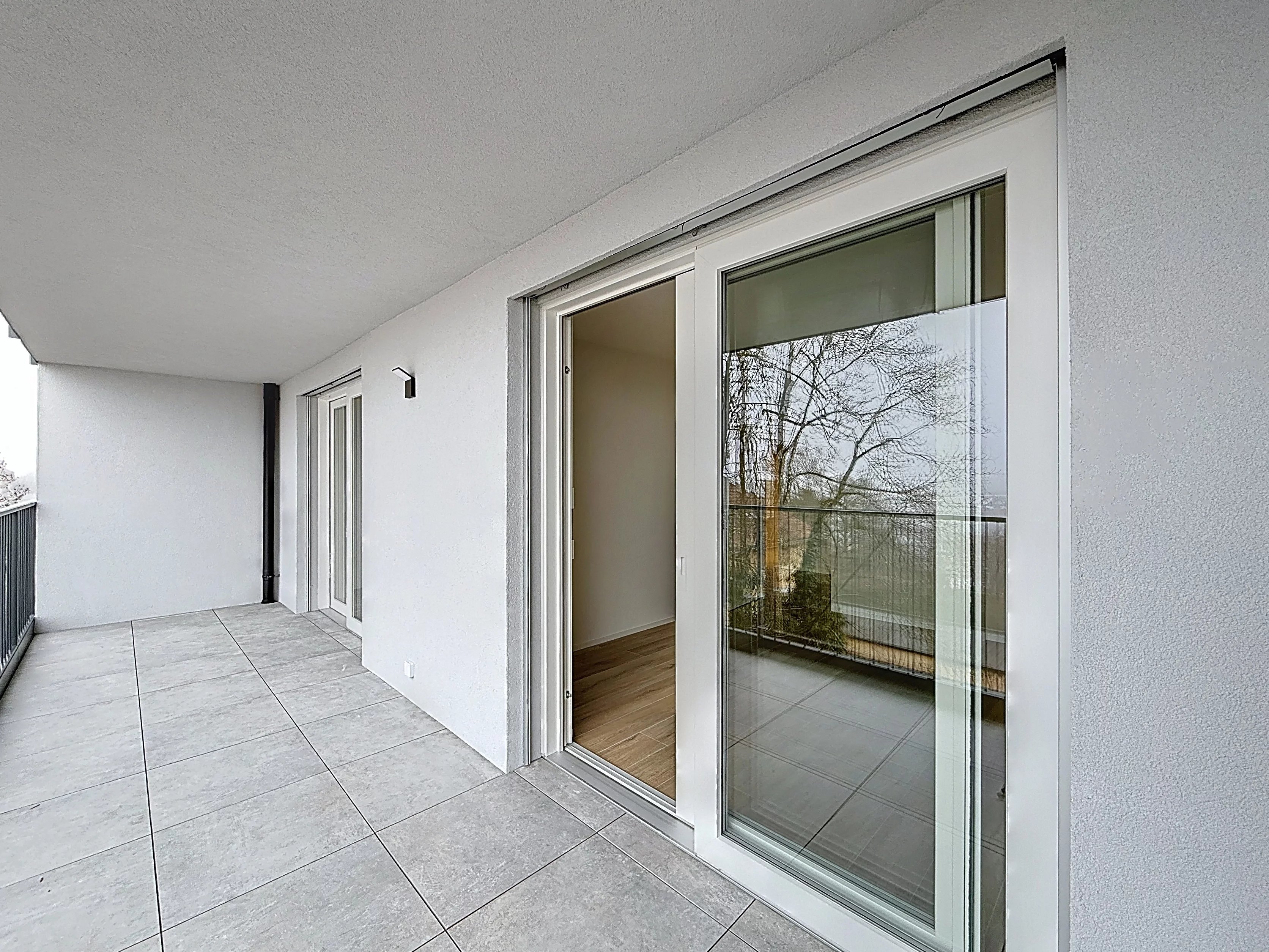 Überdachter Balkon mit bodentiefen Glastüren