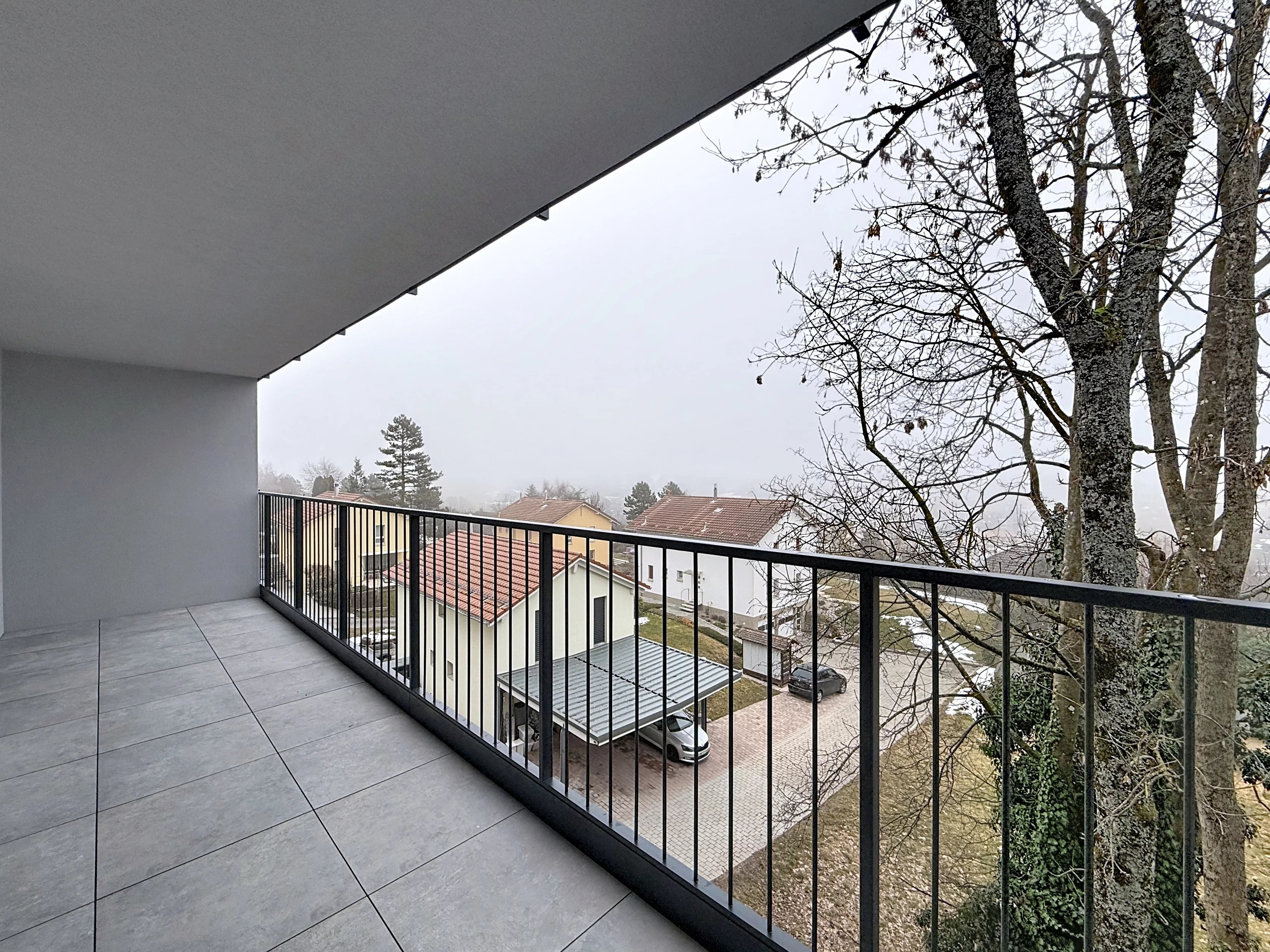 Überdachter Balkon mit Ausblick auf Wohngebiet