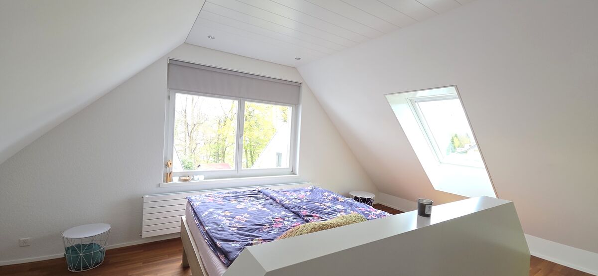 Dachgeschoss-Schlafzimmer mit Bett und Dachfenstern