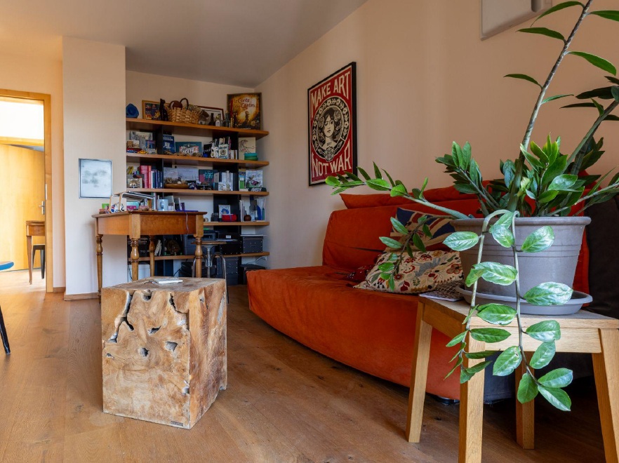 Gemütliches Wohnzimmer mit Bücherregal und orangefarbener Couch