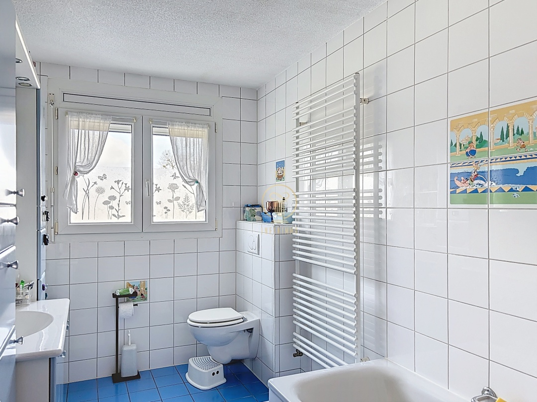 Helles Badezimmer mit weißen Wandfliesen und blauem Boden