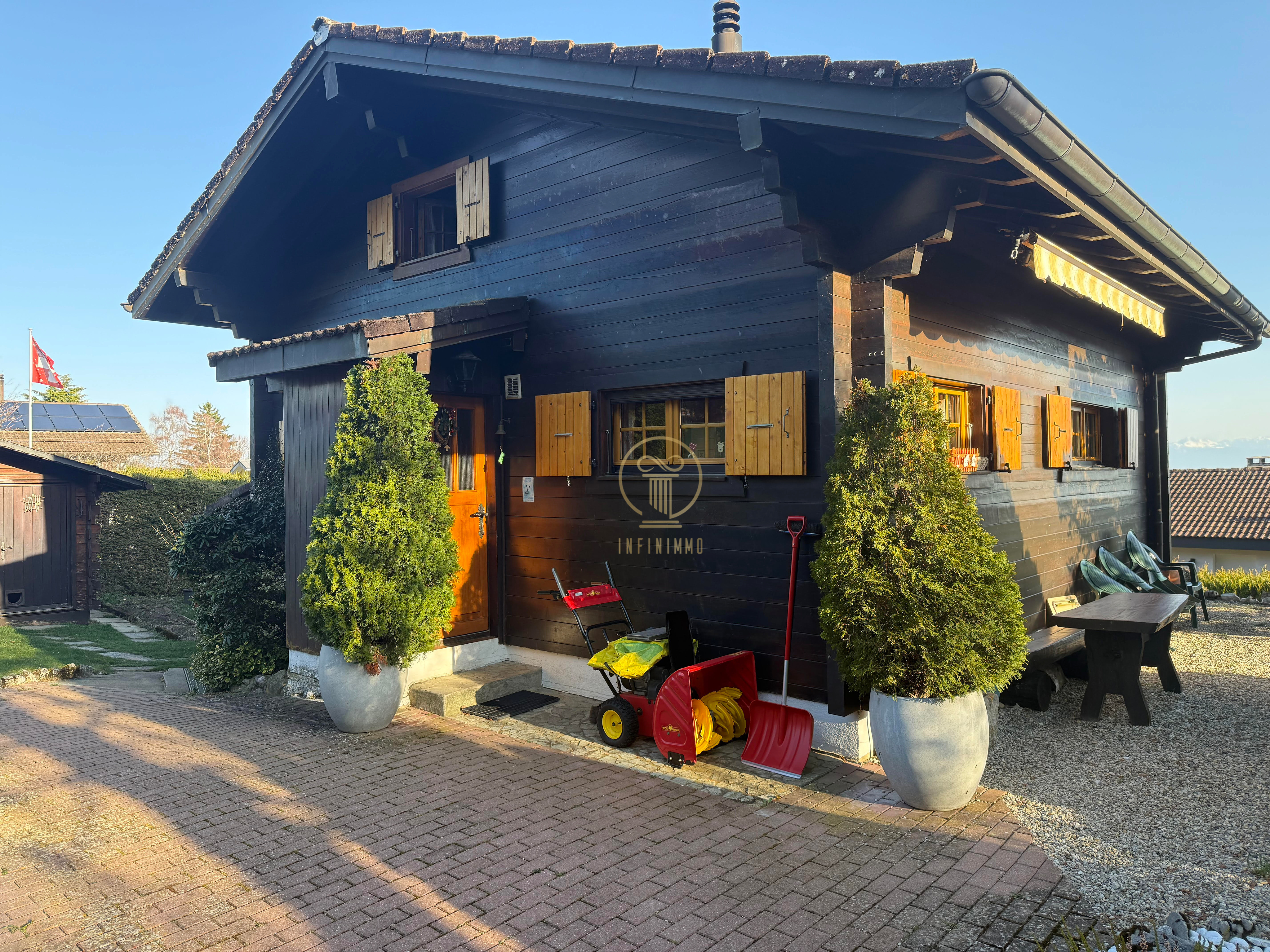 Dunkles Holzhaus mit Satteldach und Gartenbereich