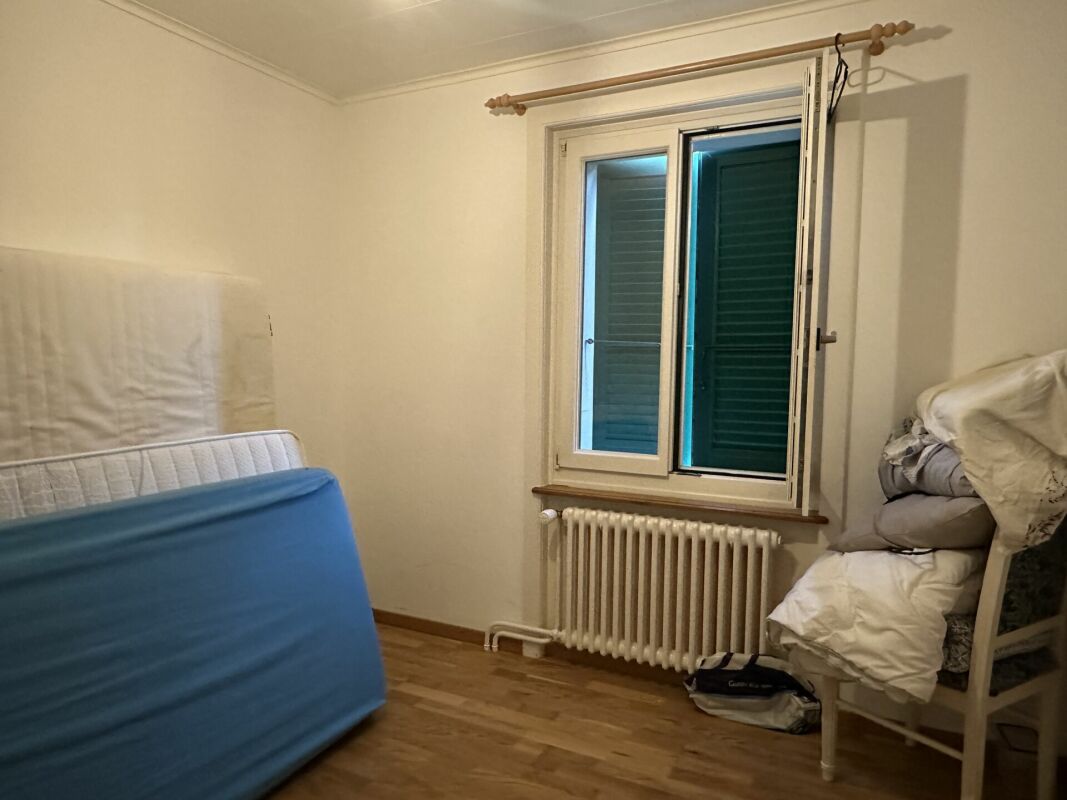 Ein schlichtes Schlafzimmer mit Fenster und Heizkörper