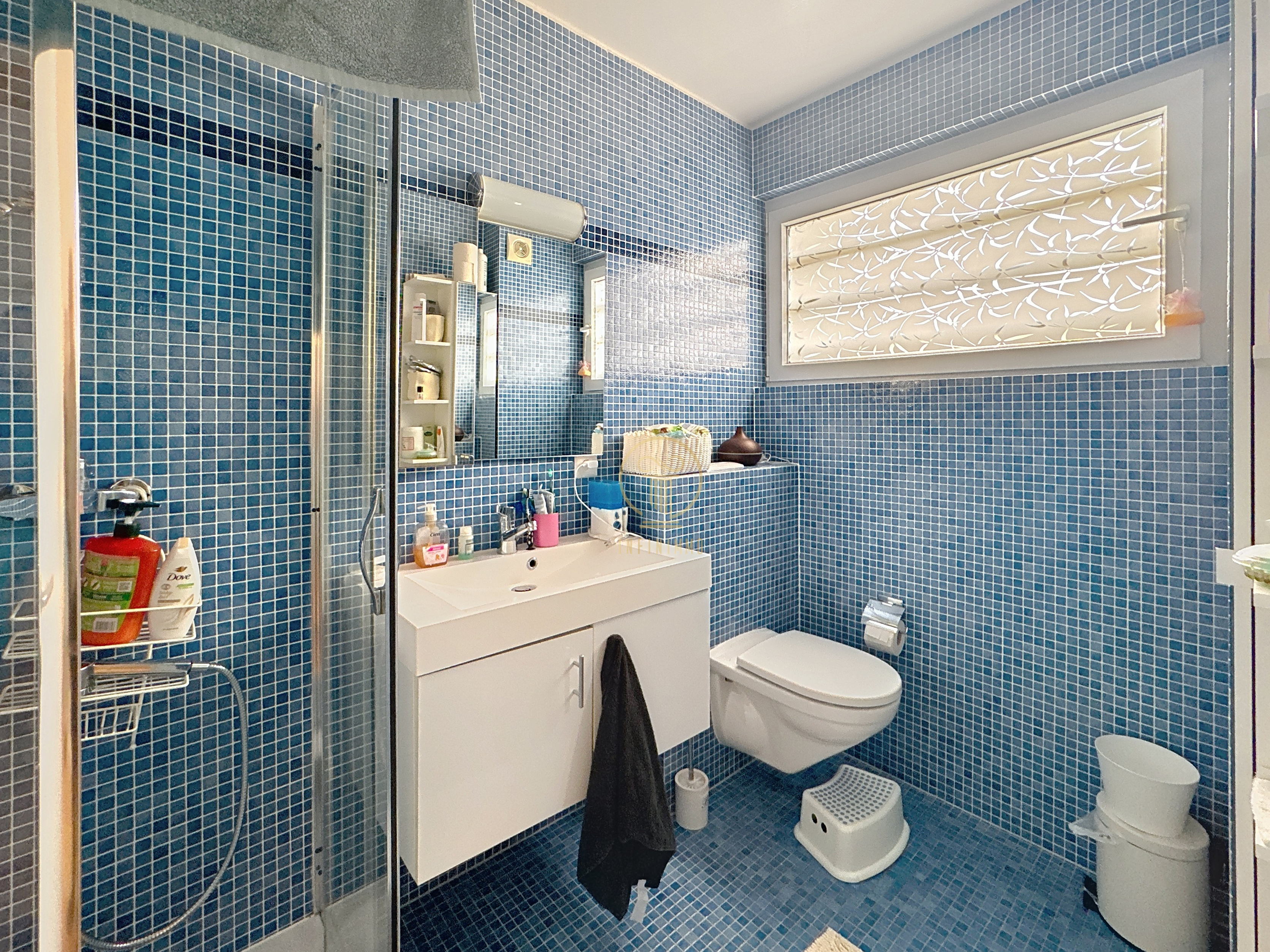 Blau gefliestes Badezimmer mit Dusche, Waschbecken und WC
