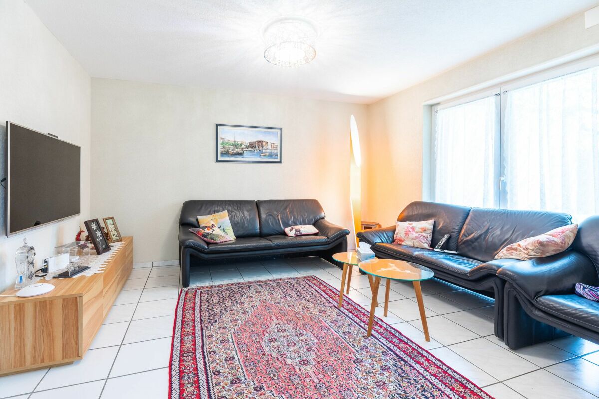 Helles Wohnzimmer mit zwei schwarzen Sofas und TV
