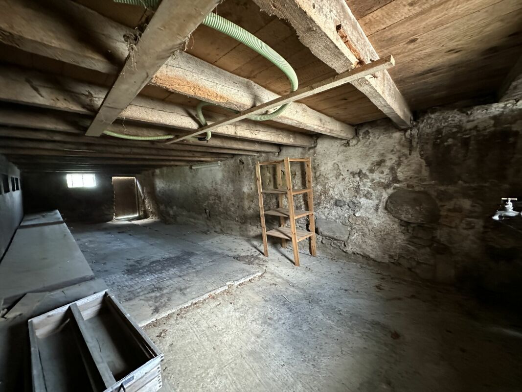 Kellerraum mit rohen Wänden und Holzbalkendecke