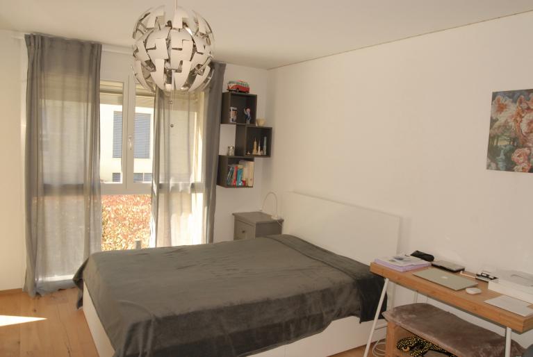 Helles Schlafzimmer mit Fenster und Schreibtisch