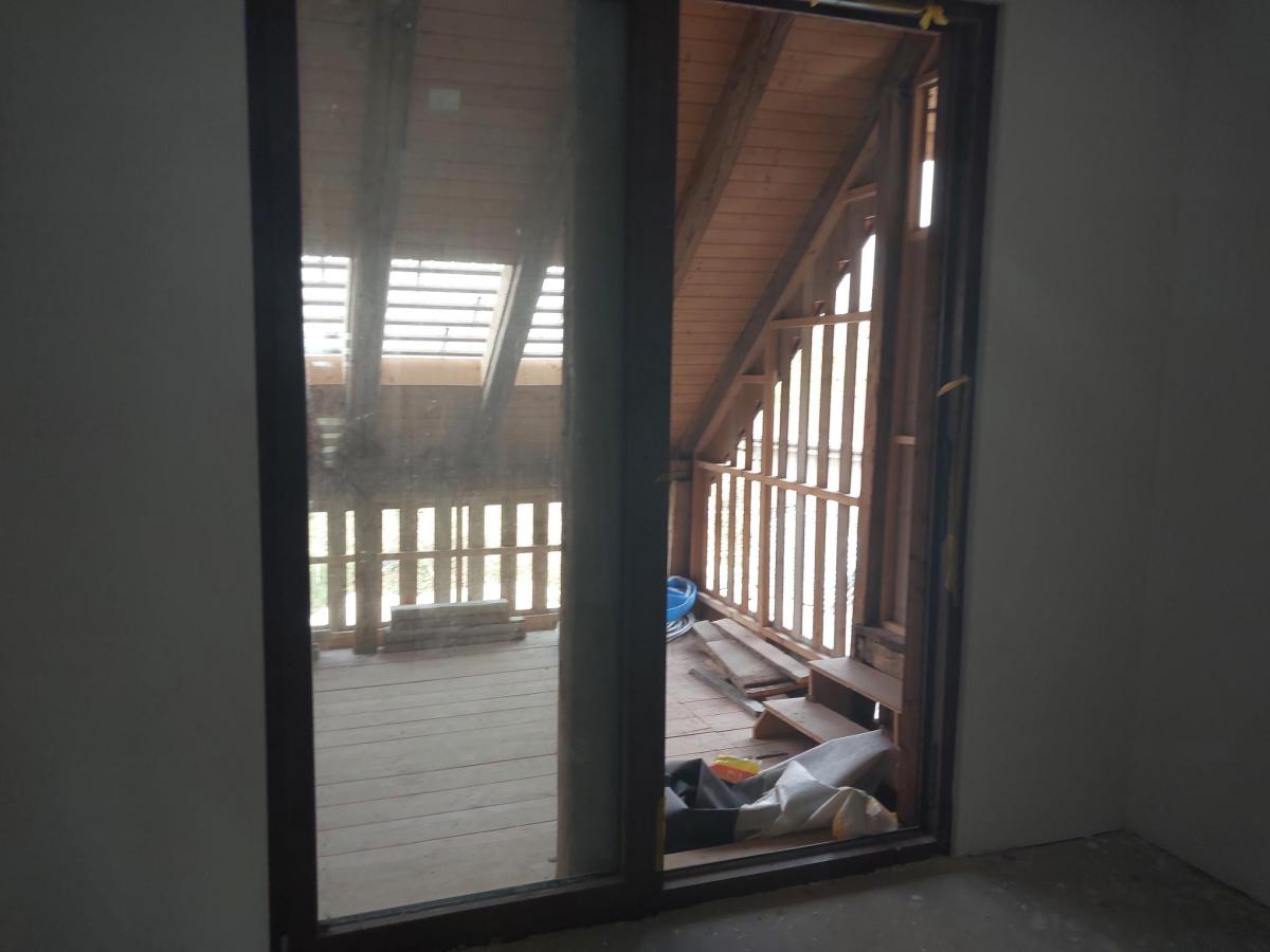 Blick durch eine Schiebetür auf eine hölzerne Loggia