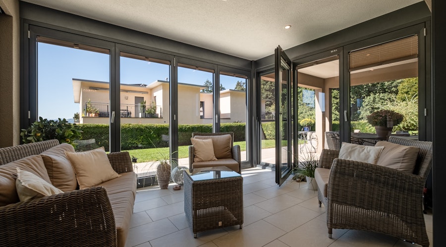 Überdachte Terrasse mit Lounge-Möbeln und Gartenblick