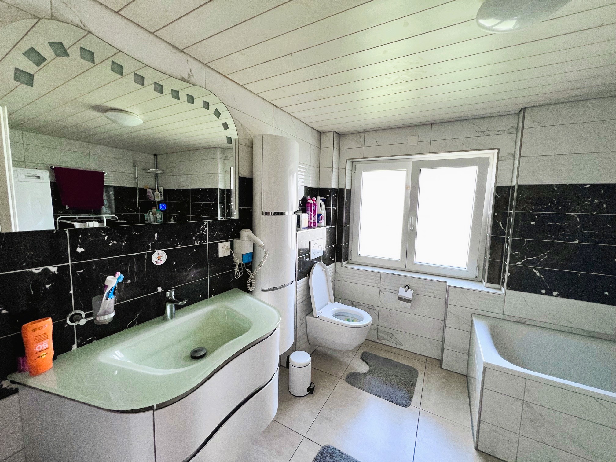 Modernes Badezimmer mit schwarzen Wandfliesen und großer Badewanne
