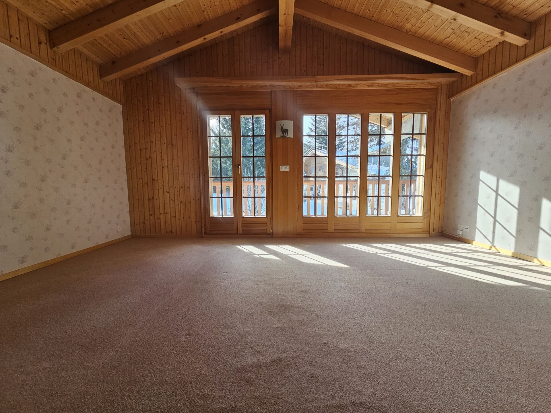 Leeres Dachgeschosszimmer mit Holzdecke und großen Fenstern