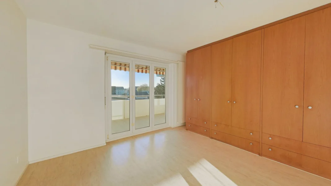 Helles Schlafzimmer mit großem Einbauschrank und Balkonzugang