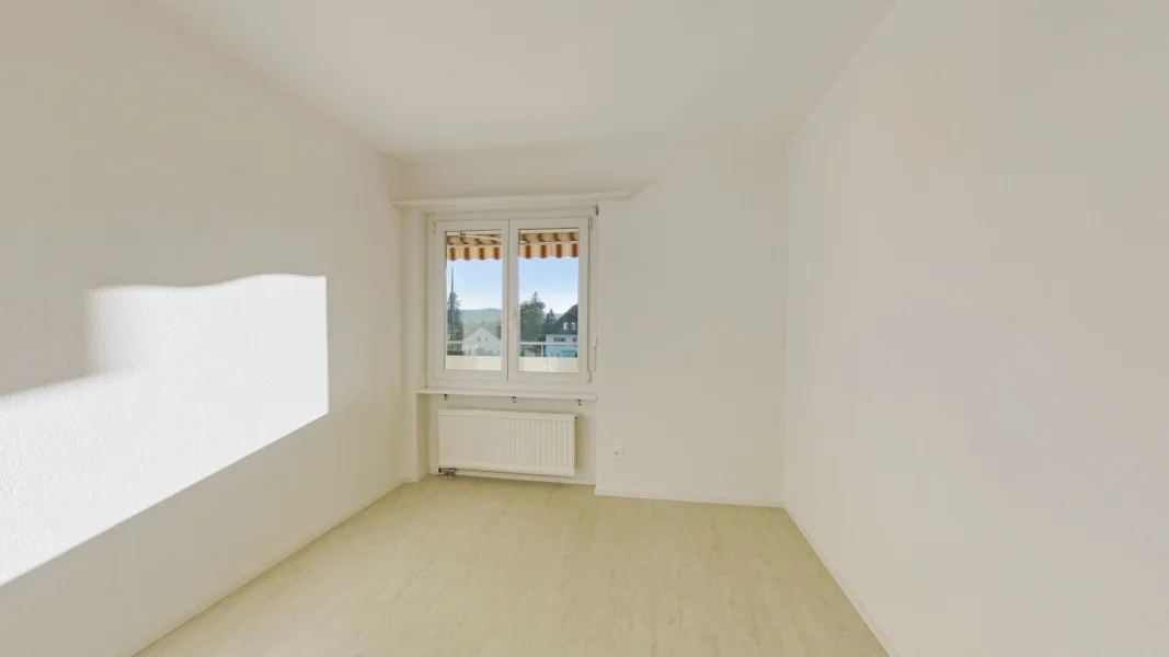 Helles, leeres Zimmer mit Fenster und Heizkörper