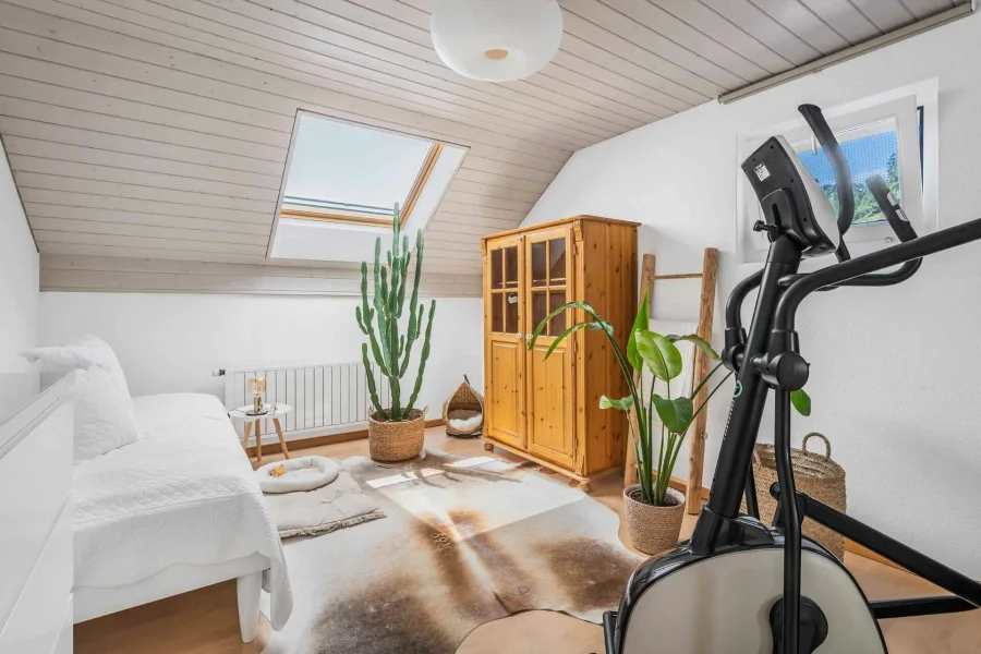 Helles Dachgeschosszimmer mit Möbeln und Trainingsgerät