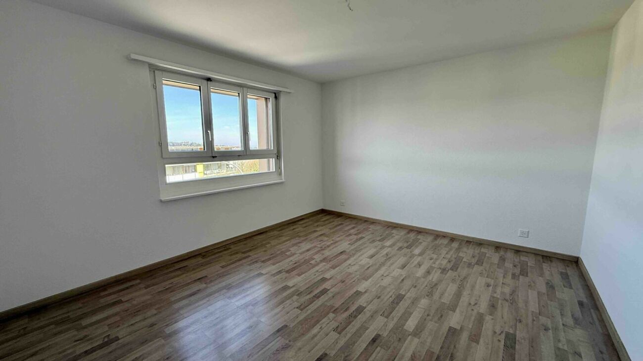 Heller leerer Raum mit Holzoptik-Boden und Fenster