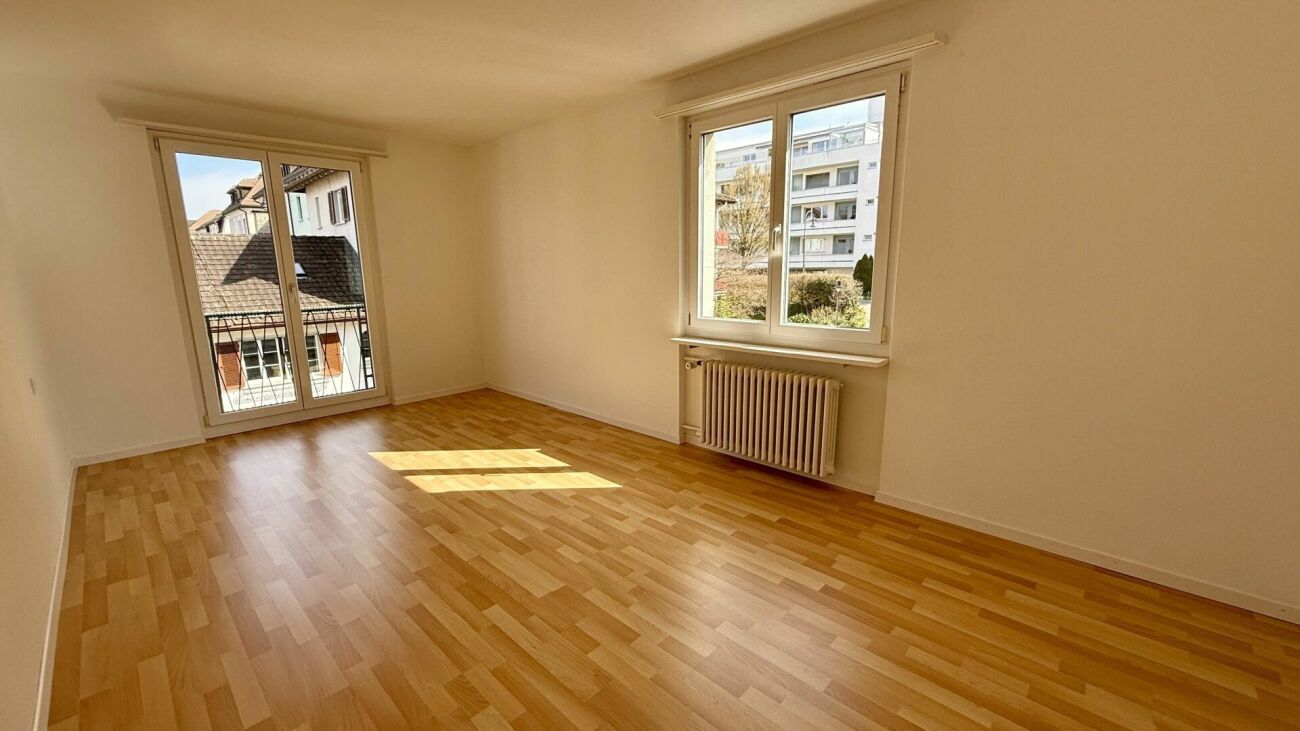 Heller leerer Wohnraum mit Parkett und Fenstern