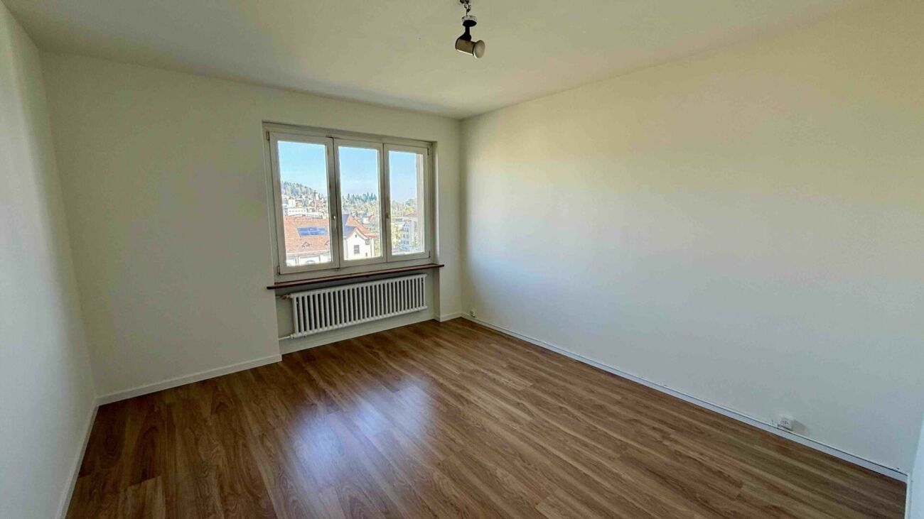 Leerer Wohnraum mit Fenster und Holzoptik-Boden