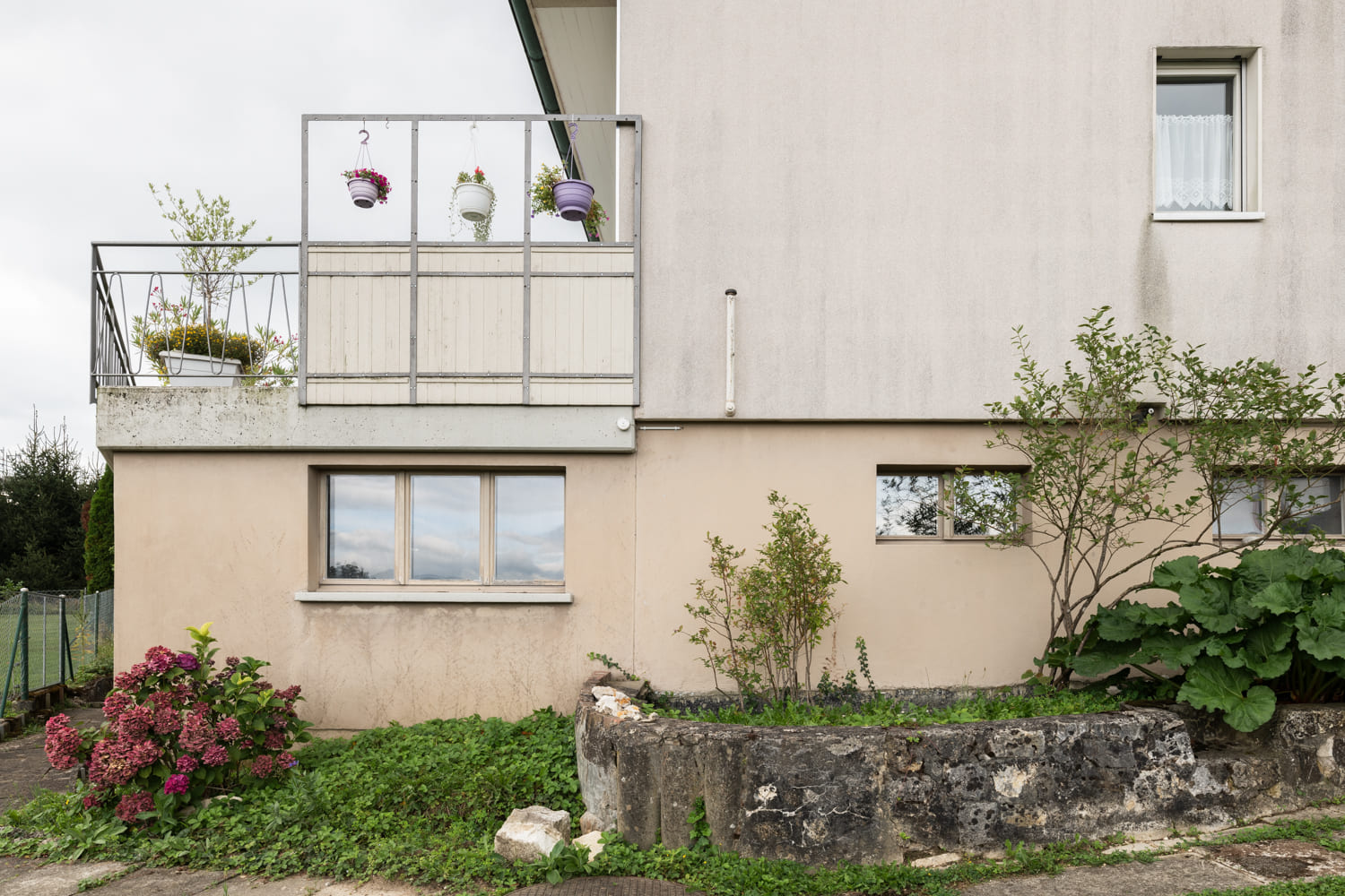 Außenansicht eines Wohnhauses mit Balkon und Garten