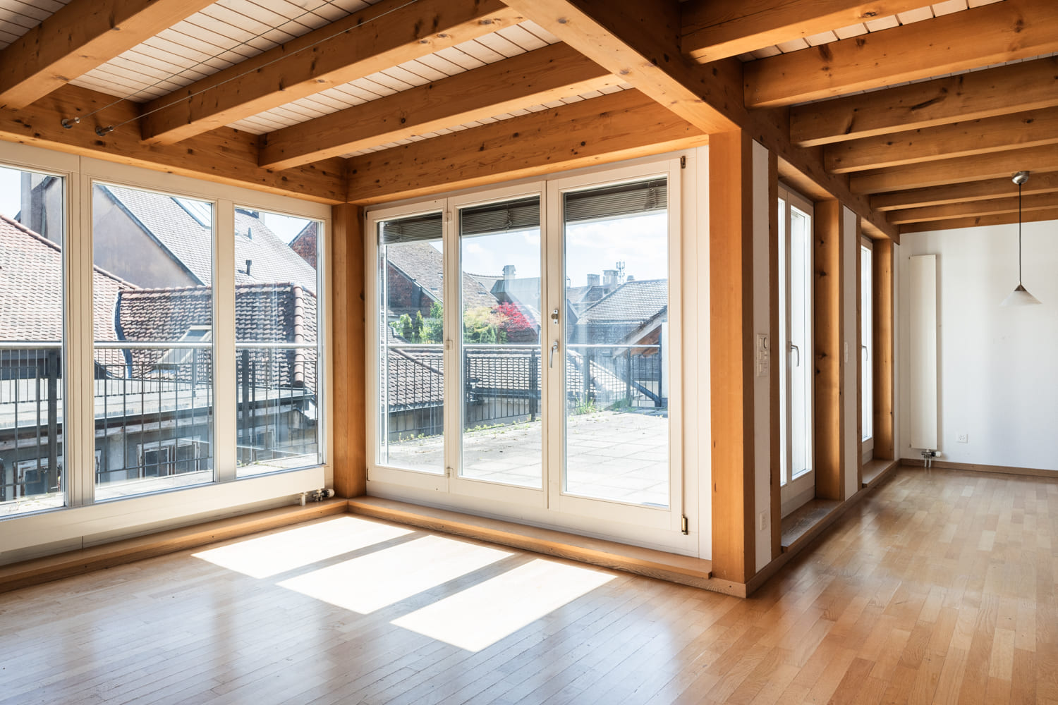 Heller Wohnraum mit Holzdecke und großen Fenstern