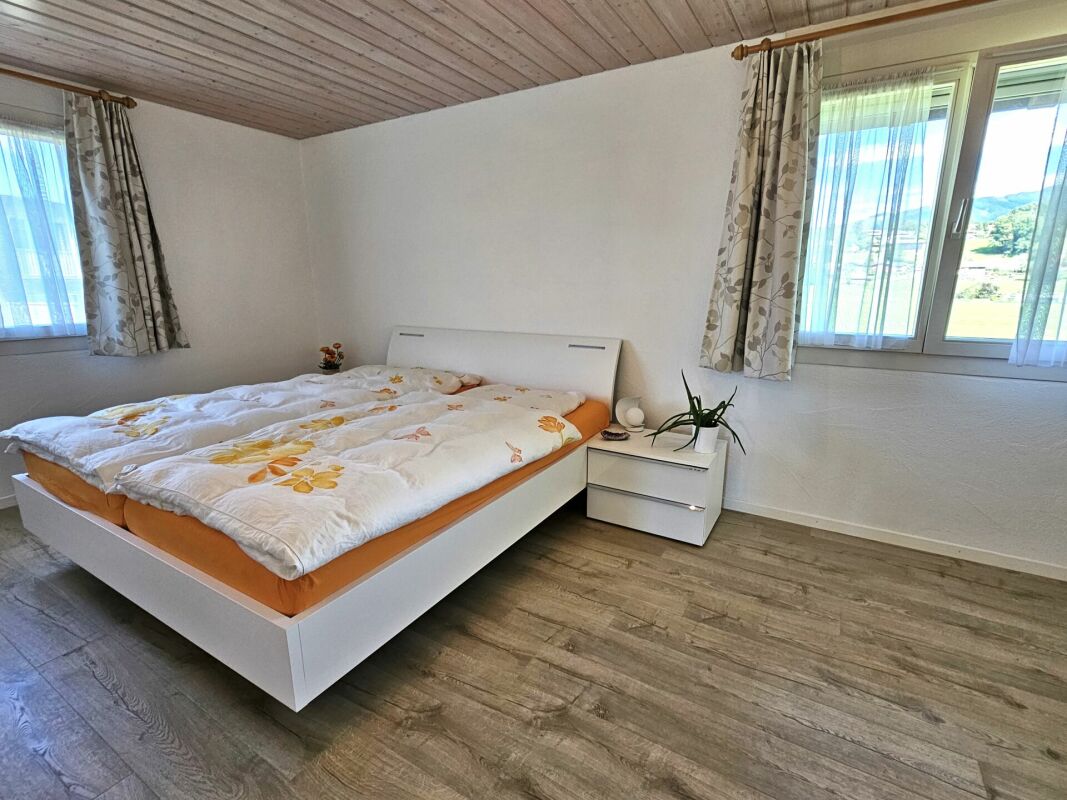 Helles Schlafzimmer mit Doppelbett und zwei Fenstern