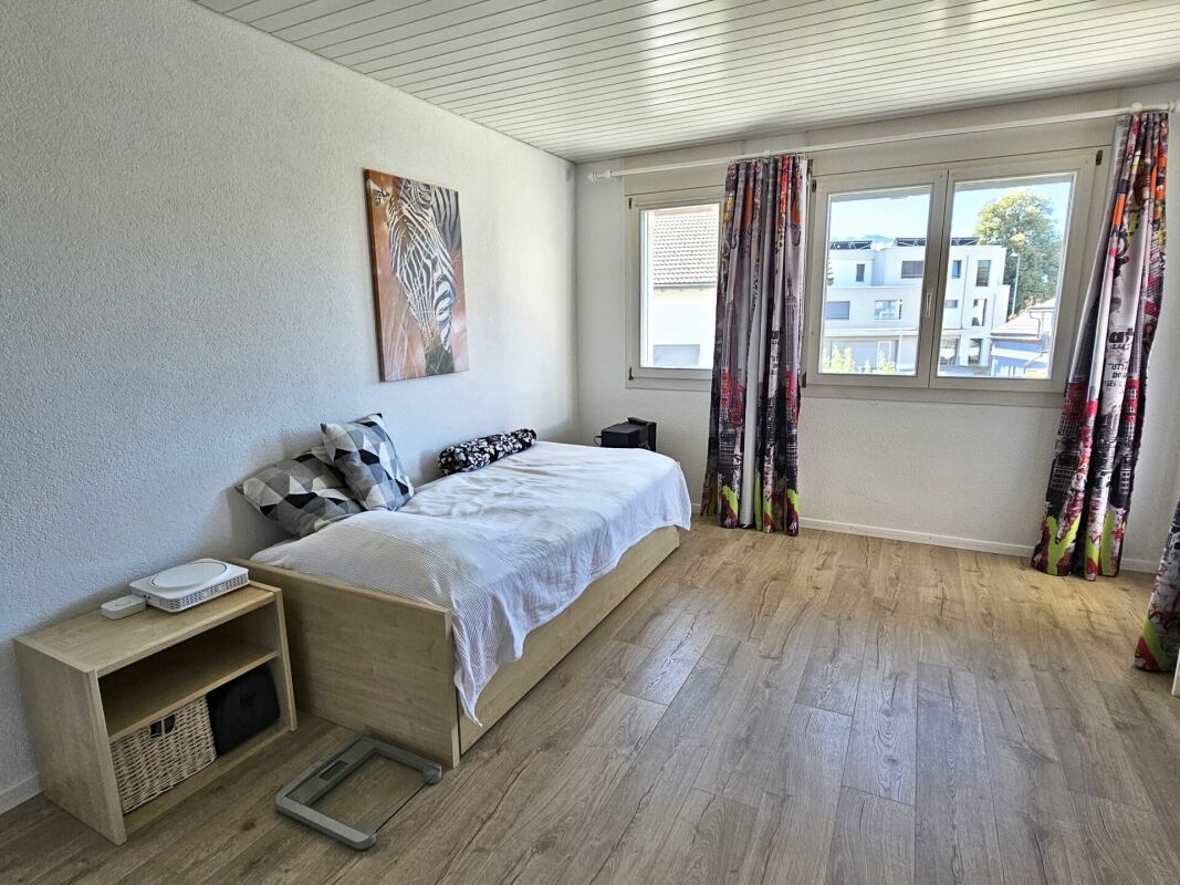 Helles Schlafzimmer mit Einzelbett und Fensterfront