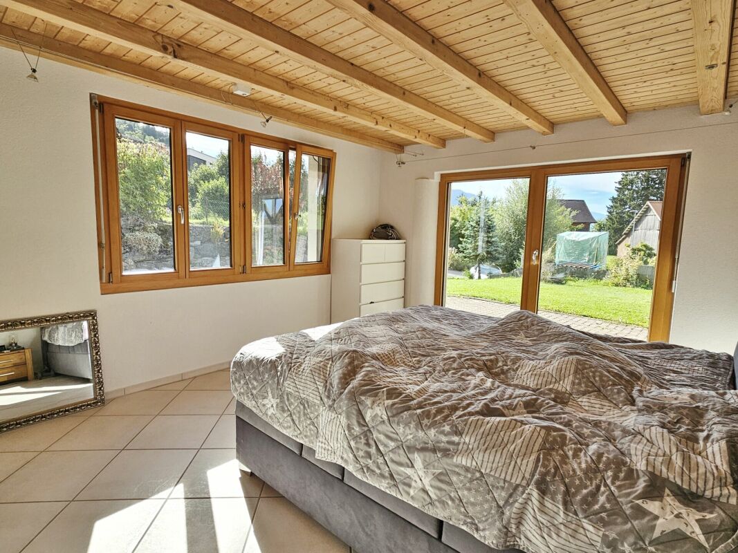 Helles Schlafzimmer mit Holzbalkendecke und Gartenblick