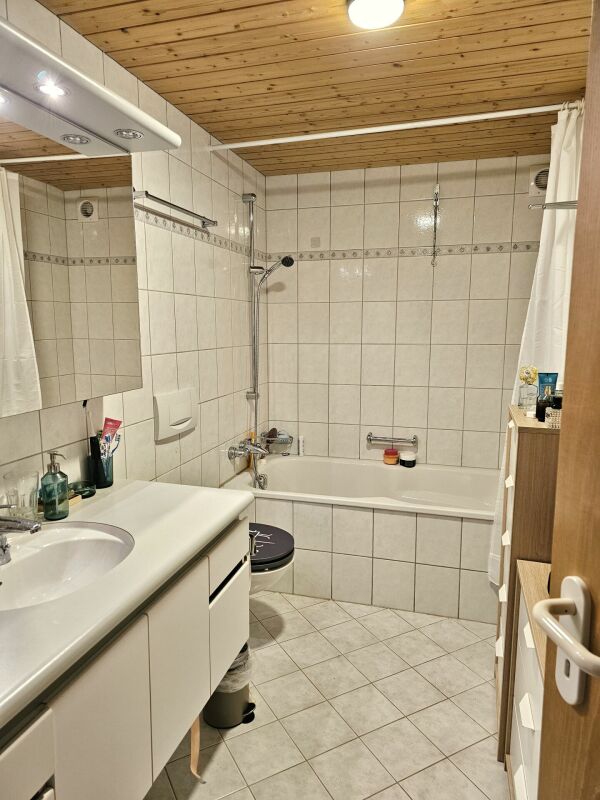 Badezimmer mit Badewanne und Holzdecke