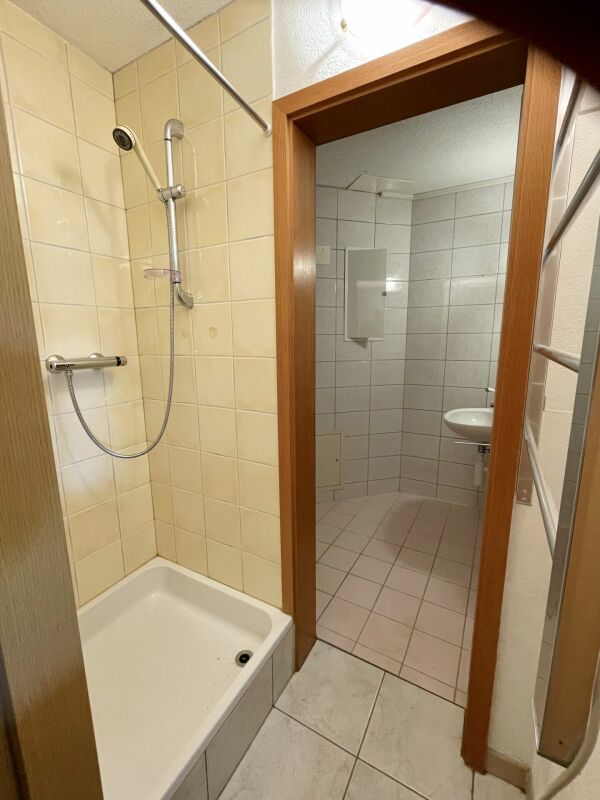 Badezimmer mit Dusche und Blick in ein separates WC