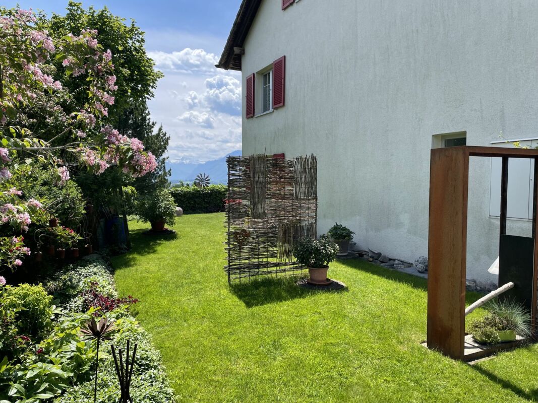 Garten mit Hausfassade und Bergblick
